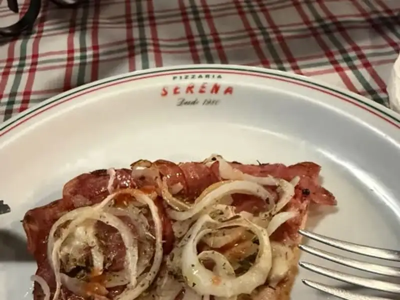 Fatia de pizza com cebola em prato da Pizzaria Serena